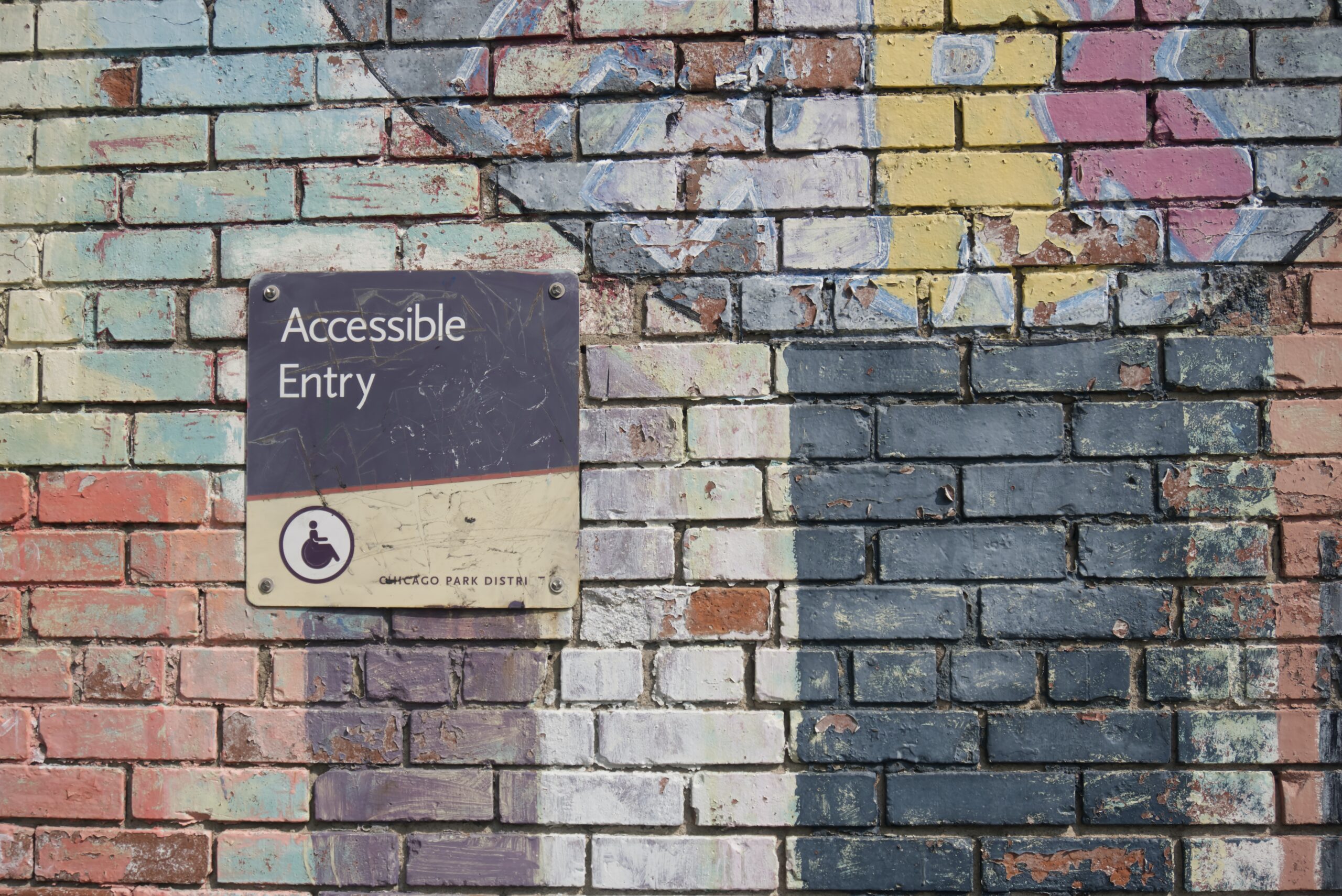 Accessible sign on brick wall covered in graffiti.